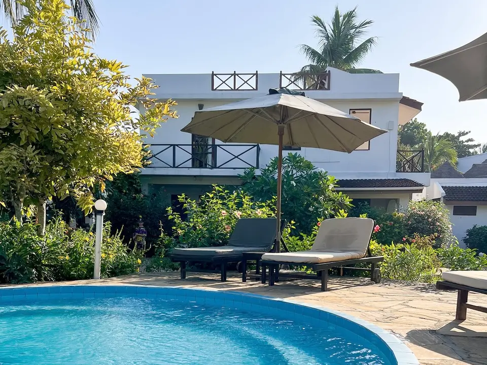 Piscine entourée de jardins tropicaux à Flame Tree Cottages Nungwi