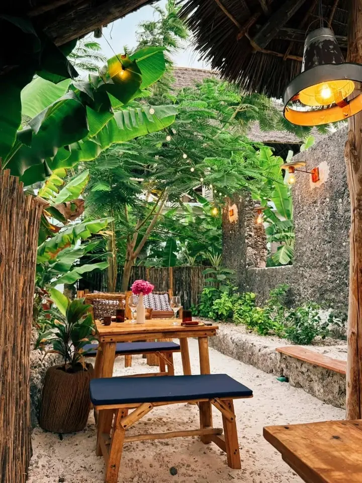 Restaurant tropical intimiste avec table en bois sous toiture traditionnelle à Jambiani Zanzibar