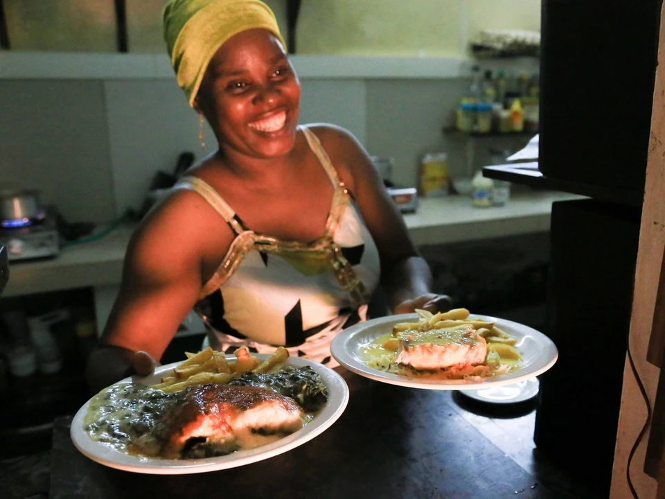 Cuisinière souriante du restaurant Chez Hassan apportant des plats locaux préparés avec soin à Jambiani Zanzibar